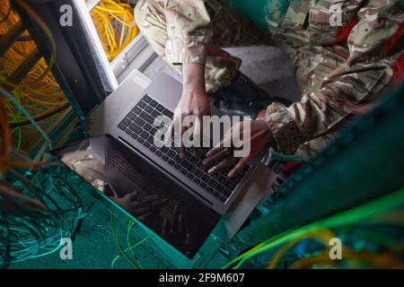 Cropped high angle portrait of young African-American woman wearing military uniform while using computer in server room Stock Photo