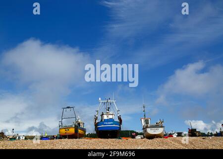 Wide angle view of 3 fishing boats on The Stade shingle beach, Hastings, East Sussex, England, UK Stock Photo