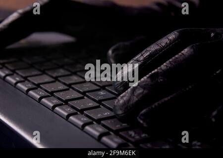 Hacker's hands on laptop keyboard. Hacking a security system. Hacker in gloves. Stock Photo