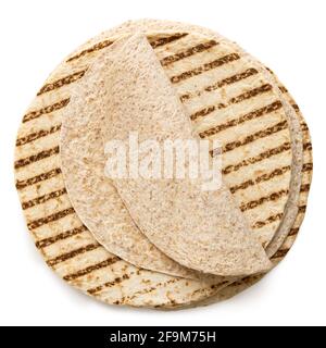Folded spelt and oat tortilla on top of a stack of plain tortilla wraps with grill marks isolated on white. Top view. Stock Photo