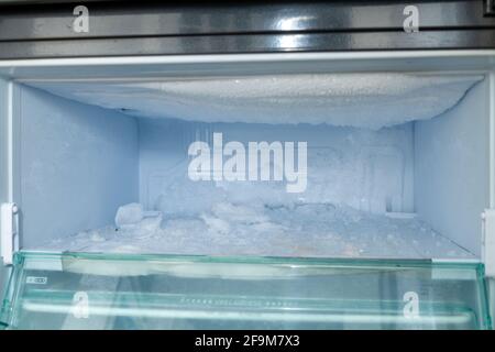 Defrosting a freezer which has a build up of ice Stock Photo
