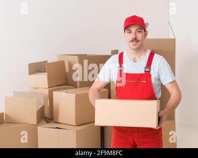 young caucasian deliveryman standing in warehouse, holding parcel Stock Photo
