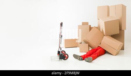 delivery man laying on floor covered in cardboard boxes Stock Photo