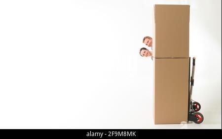 young happy couple hiding behind moving boxes, having fun. on white background Stock Photo