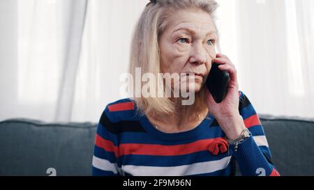 Elderly woman using smartphone to make phone call. Receiving bad news. High quality photo Stock Photo