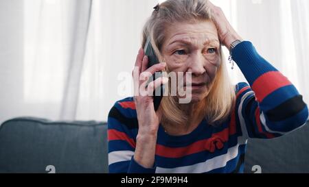 Elderly woman using smartphone to make phone call. Receiving bad news. High quality photo Stock Photo
