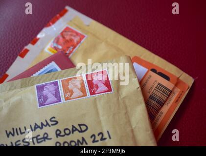 Envelopes with UK first class stamps on red texture. Stock Photo