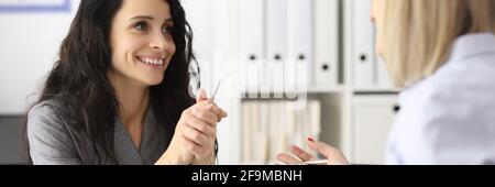 Business women smiling and talking at table in office Stock Photo