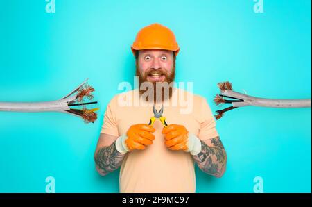 Incompetent worker electrician is unsure about his work. cyan background Stock Photo