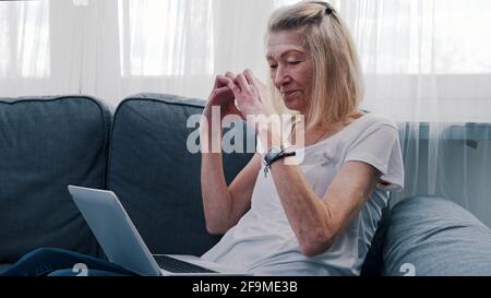 Old woman making heart shape in front of the laptop while chatting with her family. High quality photo Stock Photo
