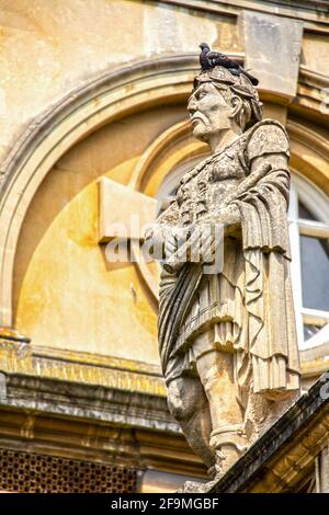 2019 07 25 Bath UK Blade nosed Roman statue in toga standing in front of ancient buildings with a pigeon roosting on his head - selective focus Stock Photo