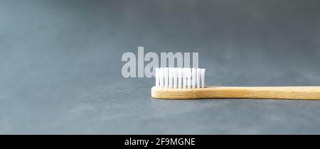 One bamboo toothbrush lies on a black background. Eco friendly stuff concept. Copy space. Horizontal orientation. Baner. Stock Photo