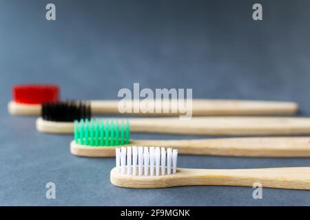 Four multi-colored bamboo toothbrushes  lie on a gray background. Eco friendly stuff concept. Copy space. Horizontal orientation. Selective focus. Stock Photo