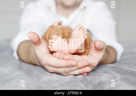 Closeup of father dad holding little newborn baby feet in his hands. Stock Photo