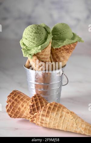 two pistachio ice creams on white marble in a metal bowl Stock Photo
