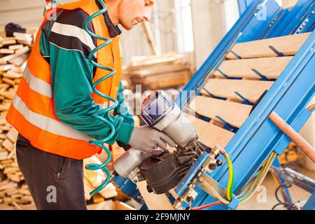 Professional furniture production factrory worker using pneumatic hammer Stock Photo