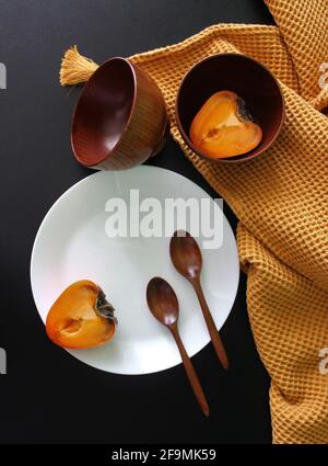 A white plate, two wooden cups, a pair of wooden spoons on a black bac Stock Photo