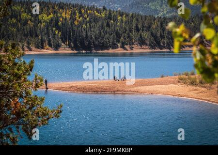 Fishermen on sand bar at Crystal Creek Reservoir on the slopes of Pikes Peak near Colorado Springs USA with evergreen forest in background - Selective Stock Photo