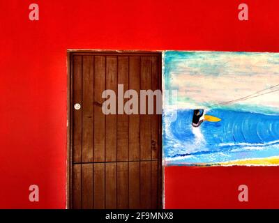 old wooden door in red parde and with blue sky and painted kite surf. Stock Photo