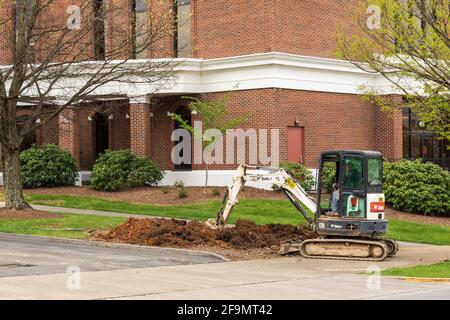 KINGSPORT, TN, USA--8 APRIL 2021: A Bobcat back hoe digs in front of a brick building. Stock Photo