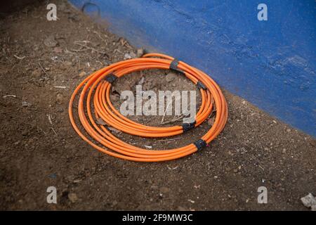 Device for modern fiber optic cables lies on the floor of a house wall Stock Photo