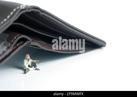 Poor man beggar with empty wallet no money cash. Miniature tiny people toys photography. isolated on white background. Stock Photo