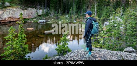 Hiker looking down to Embryo Lake with Taylor Peak in the far distance Stock Photo