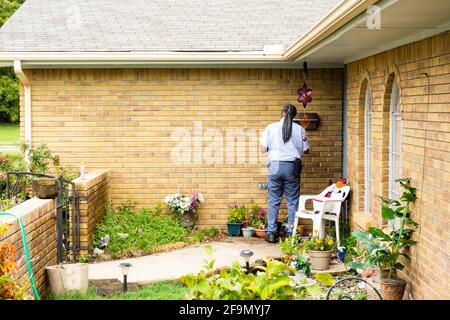 Mail carrier delivering mail to a mailbox hanging near the front door of a home. USA Stock Photo