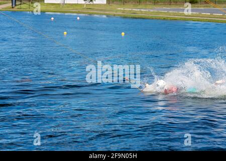 Man learning to wakeboard at a cable ski park and not succeeding as he falls off with a splash Stock Photo