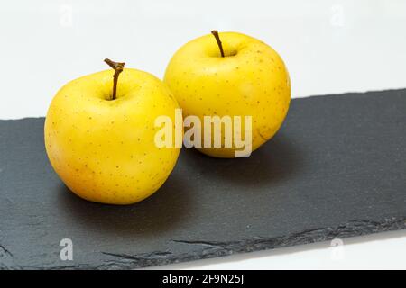 Yellow apples on the black stone board and white background. Organic ...