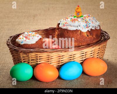 Easter cakes in wicker basket and colorful Easter eggs . Stock Photo