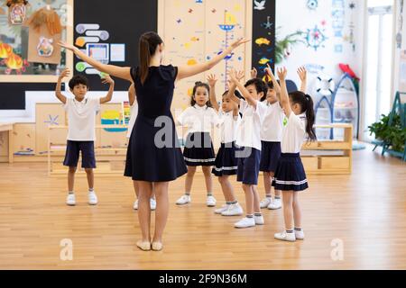 Teacher teaching children dancing in classroom Stock Photo