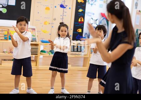 Teacher teaching children dancing in classroom Stock Photo