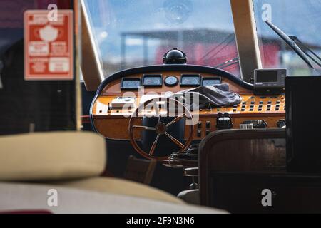 View of the varnished wooden steering wheel of a marine yacht, control devices, gauges, buttons and direction arrows Stock Photo
