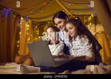 Mother and two daughter children watching funny cartoon on laptop before bedtime Stock Photo