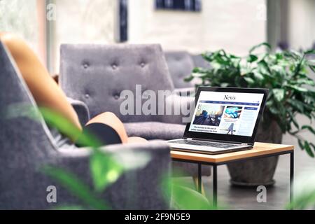 Laptop with news website in screen on table in business office, corporate lounge or hotel lobby. Company wireless wifi. Modern cafe or workplace. Stock Photo
