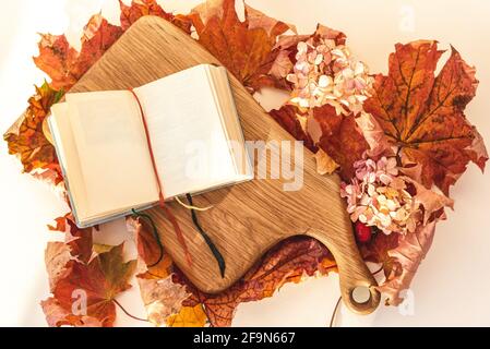 Open diary on wooden board and fall maple leaves Stock Photo