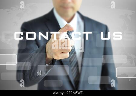 Businessman pointing to CONTACT US sign on virtual screen Stock Photo