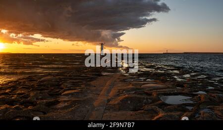 Beautiful sunset over a windmill-shaped lighthouse, Swinoujscie, Poland Stock Photo