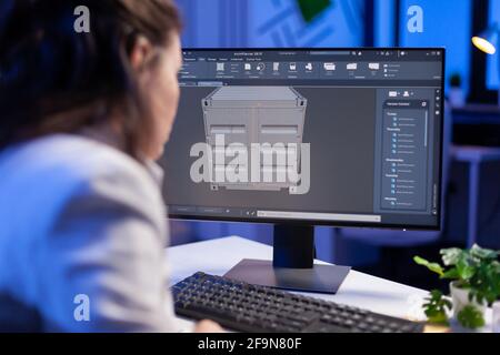 Engineer looking at cad software 3D prototype design concept of container working overtime in construction company. Overworked woman studying in office new project model using innovative technology Stock Photo
