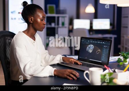 Workaholic blackwoman drawing cad technical prototype developing modern shape using engineering technology. Engineer working late at night for construction industry looking at digital display on laptop Stock Photo