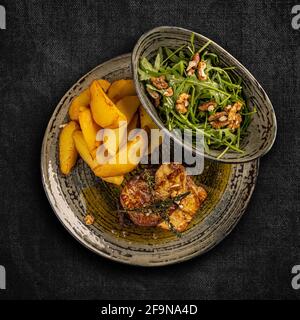 Steak with grilled duck liver garnished with potato wedges and aragula, top view Stock Photo