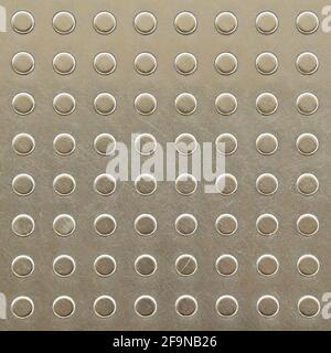 Dots on metal plate as tactile paving or signal for blind people on footpath or platform Stock Photo