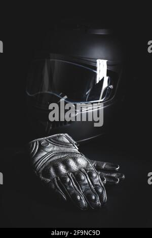Black leather motorcycle gloves and helmet on a black background. Stock Photo