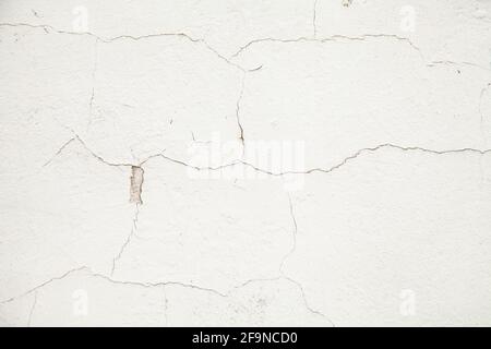 White wall with cracks. Cracks texture on a white abstract background. Cracked plaster on the wall Stock Photo