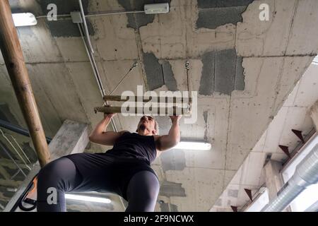 athlete trains his strength by doing pull-ups at the gym, sport and active lifestyle concept Stock Photo