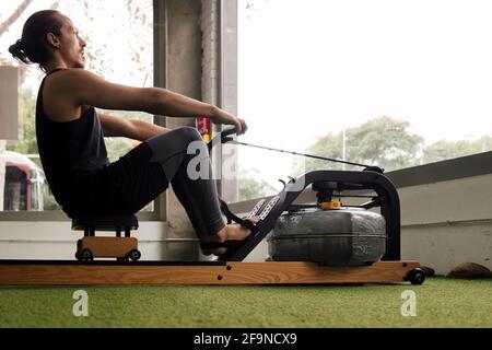 sporty man training his strength in the gym with a water rowing machine, active and sporty lifestyle concept Stock Photo