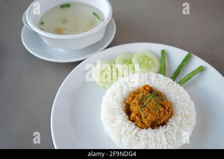 Close up Stir fry pork with spicy curry paste in southern Thai style served with white rice and clear soup Stock Photo