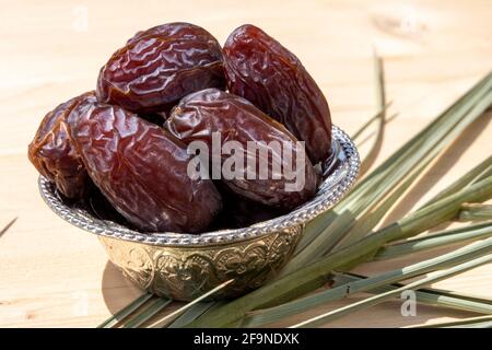 Religious Muslim festival and holy month of Ramadan, EID MUBARAK, concept: Close up on an ornate metallic bowl with many dried date fruits. Stock Photo