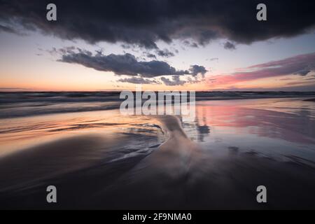 Beautiful sunset over bredsand, a sandy beach, patterns after waves in the sand Stock Photo